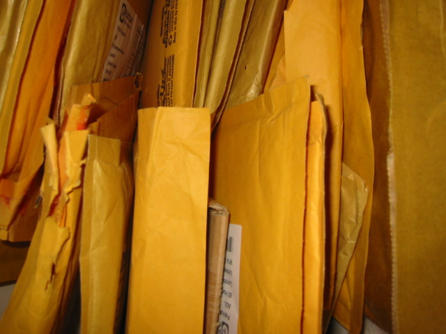 A pile of padded manila envelopes, several torn open